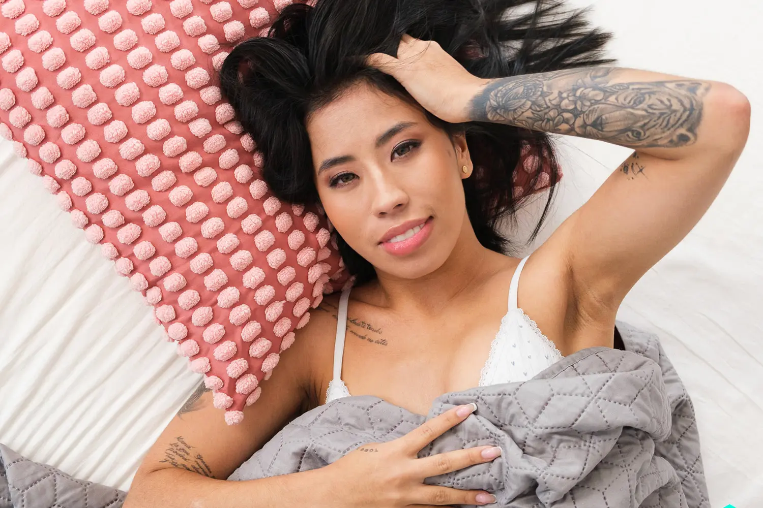 Scene preview of a tattooed performer beside a pink pillow